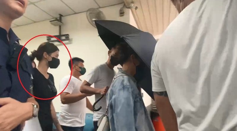 崁頂鄉代會主席楊芷瑜在白衣人撐傘刻意保護下，走進解剖室，由檢警確認丈夫陳昫豪的死者身分。石秀華／攝影