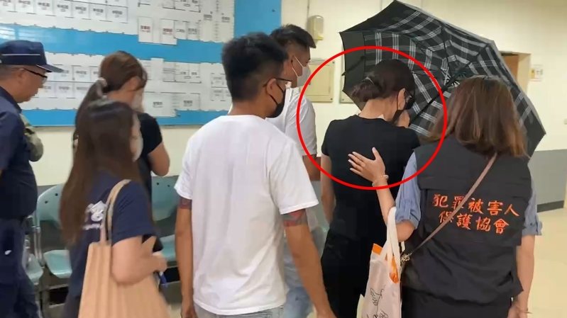 崁頂鄉代會主席楊芷瑜在白衣人撐傘刻意保護下，走進解剖室，由檢警確認丈夫陳昫豪的死者身分後步出解剖室，眼眶泛紅，手摀著口罩，低聲啜泣。石秀華／攝影