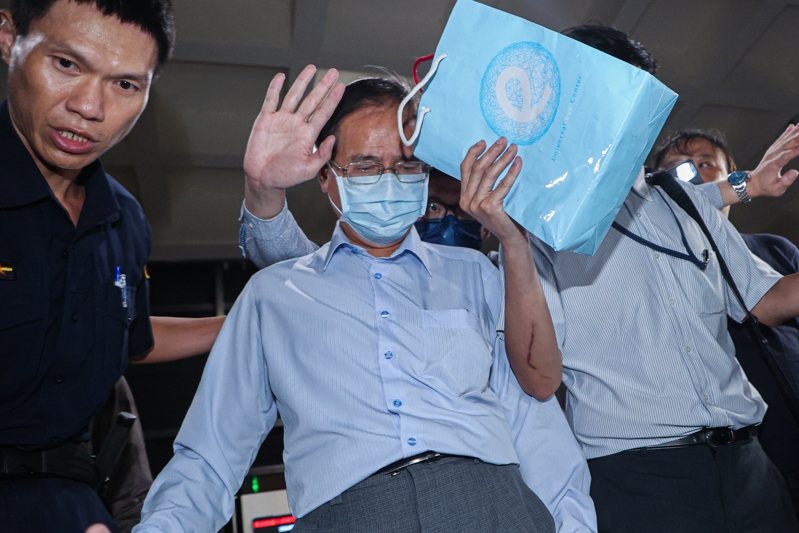 國民黨立委鄭天財（中）涉嫌收賄，遭台北地檢署搜索約談。檢方訊後諭知鄭天財200萬交保，限出境出海。今天凌晨鄭天財與同行人員快步離開北檢，鄭低頭神色落寞，不發一語，兩名男子在側試圖用紙袋遮掩鄭天財。記者曾原信／攝影