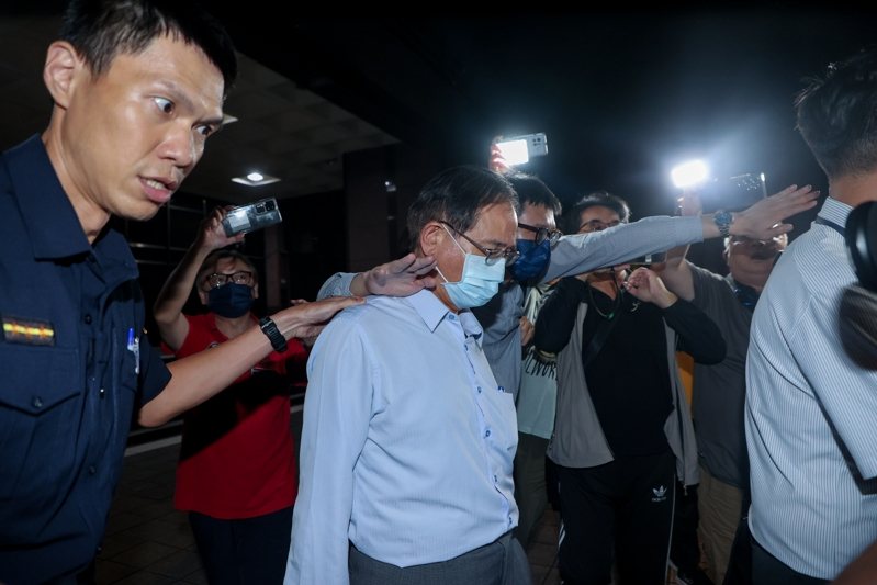 國民黨立委鄭天財（中）涉嫌收賄，遭台北地檢署搜索約談。檢方訊後諭知鄭天財200萬交保，限出境出海。今天凌晨鄭天財與同行人員快步離開北檢，鄭低頭神色落寞，不發一語，兩名男子在側試圖用紙袋遮掩鄭天財。記者曾原信／攝影