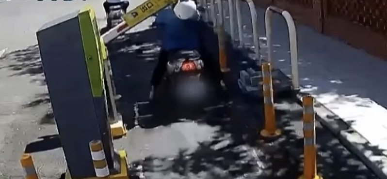73歲婦人騎機車22日上午9點44分，要離開台中榮民總醫院嘉義分院停車場，疑似硬闖，結果臉撞柵欄，手又催油門失控，當場摔在路中央受傷，全程被監視器拍下。記者魯永明／翻攝