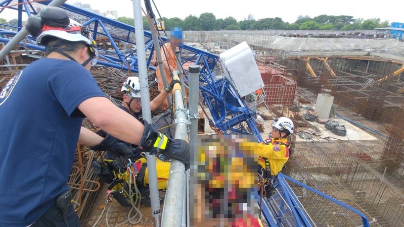 高雄三井商場工程今天上午9時許傳出工安意外，工地施工的藍色吊塔突倒塌掉落橫躺在鷹架、模板和一片鋼筋之中，意外造成工人1死1重傷；圖為消防員救援畫面。記者石秀華／翻攝