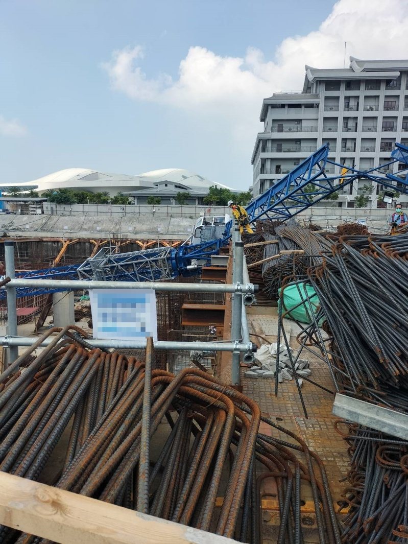 高雄三井商場工程今天上午9時許傳出工安意外，工地施工的藍色吊塔突倒塌掉落橫躺在鷹架、模板和一片鋼筋之中，意外造成工人1死1重傷；圖為消防員救援畫面。記者石秀華／翻攝