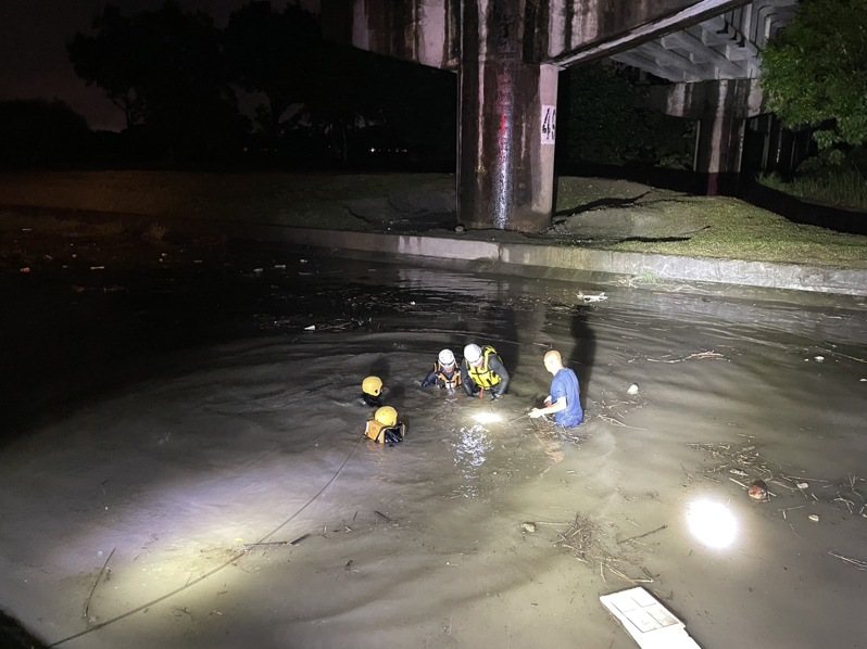 屏東市河濱公園舊鐵橋下方一轎車不慎墜落溝渠後沉入水中，救難人員花近1小時將困在車內年約70歲的男子救出，不過已經無生命跡象。圖／屏東縣消防局提供