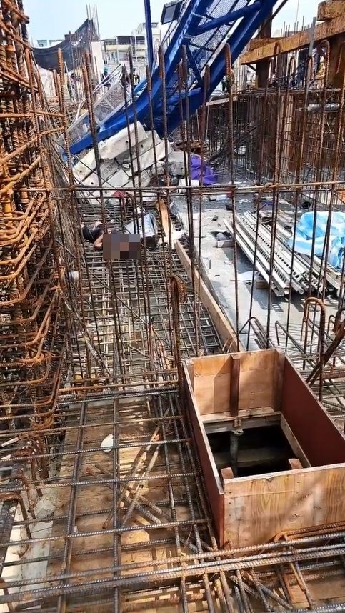 高雄三井商場工程今天上午9時許傳出工安意外，工地施工的藍色吊塔突倒塌掉落橫躺在鷹架、模板和一片鋼筋之中，意外造成工人1死1重傷。圖／取自記者爆料網