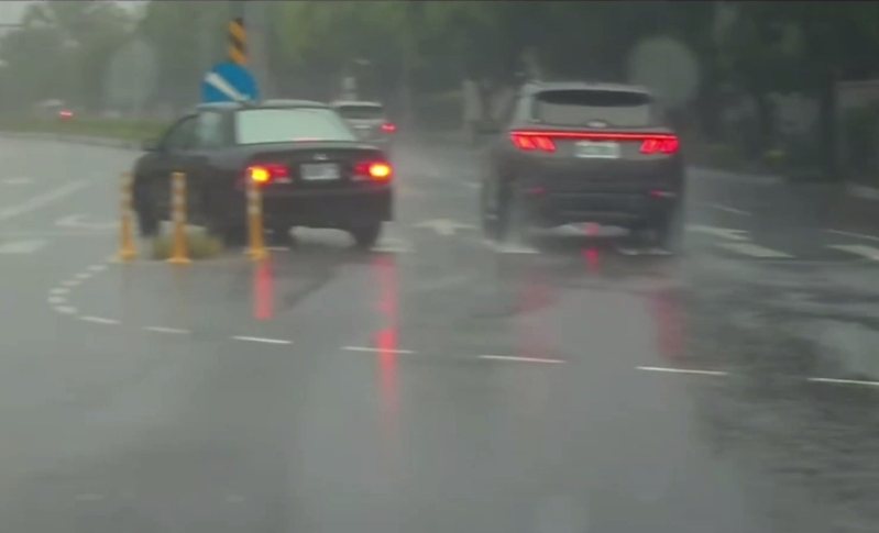 新北市林口地區昨天下午下大雨，1輛黑色轎車在醒吾科技大學校門斜前方，飛快行駛中猛然橫切2線車道，從外線直接迎面撞上中央分隔島前緣，後方休旅車迅速閃過，沒有發生二次擦撞。圖／翻攝爆料公社二社