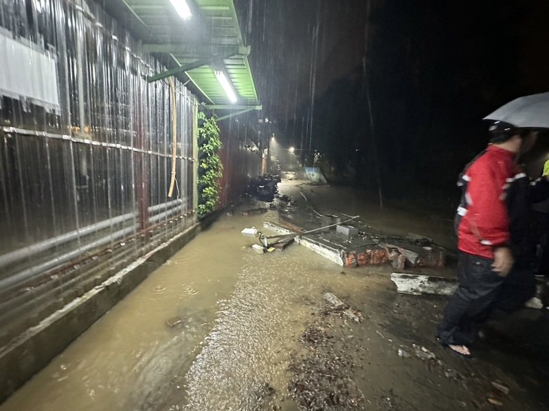 新北市汐止區茄苳路中央標準局辦公廳舍的圍牆，今晚被洪水推倒，積水宣洩而出，波及停在圍牆外中華街的機車，並造成積水。圖／張錦豪提供