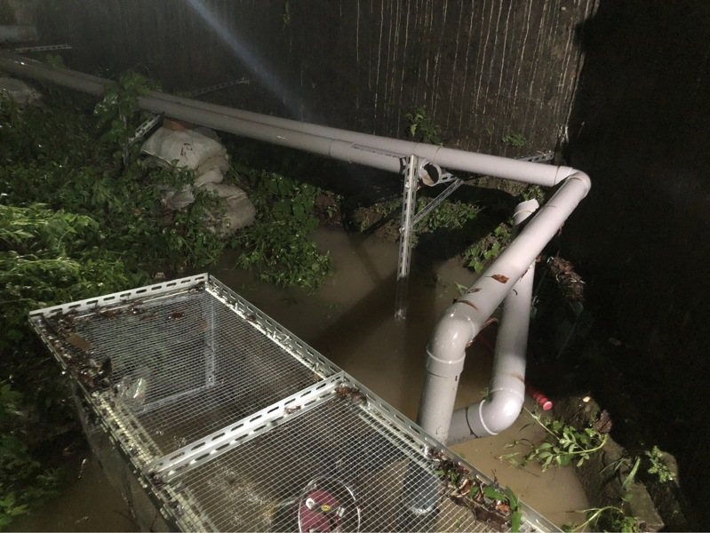 新北市汐止區茄苳路中央標準局辦公廳舍的圍牆，今晚被洪水推倒，積水宣洩而出，波及停在圍牆外中華街的機車，並造成積水。記者邱瑞杰／翻攝