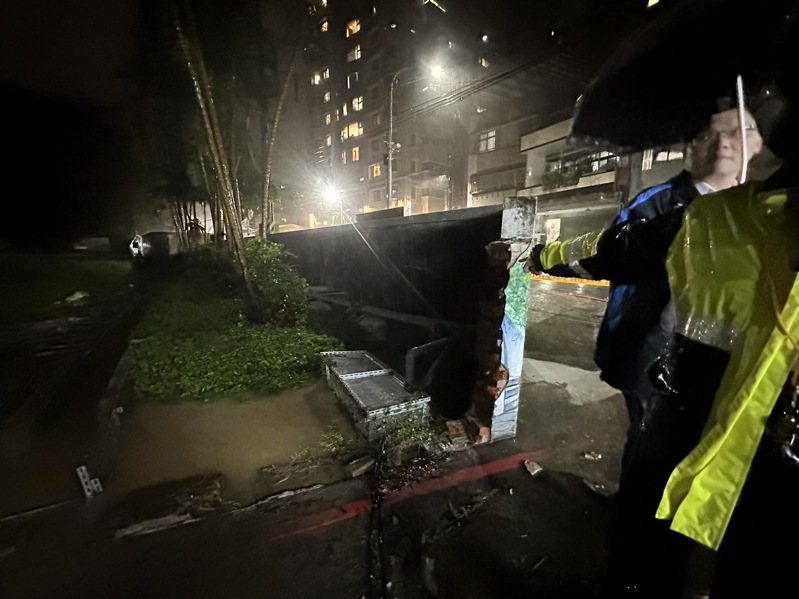 新北市汐止區茄苳路中央標準局辦公廳舍的圍牆，今晚被洪水推倒，積水宣洩而出，波及停在圍牆外中華街的機車，並造成積水。圖／張錦豪提供