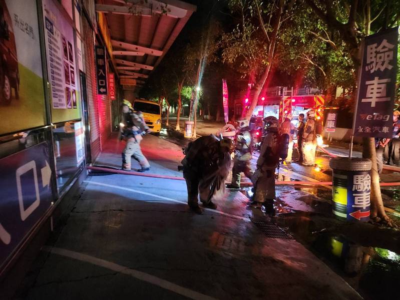 台南市仁德區中山路一家驗車場，今天凌晨突然起火，消防人員拉水線進入滅火。記者黃宣翰／攝影