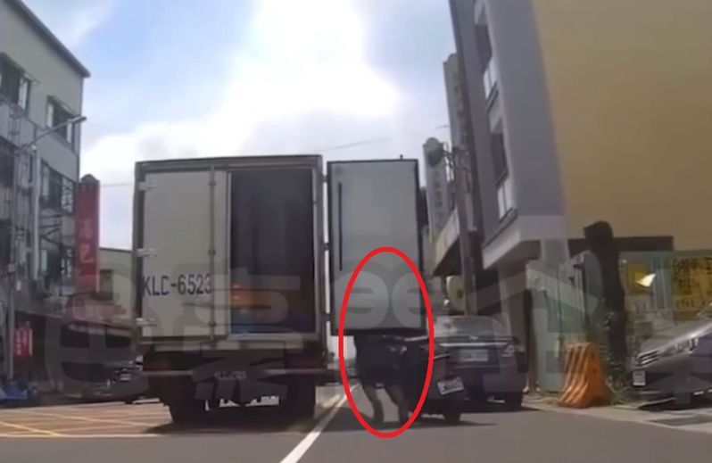 台中太平一輛物流車後門沒關妥，路邊男騎士（紅圈處）慘被車門砸中背部。圖／翻攝「黑色豪門企業」