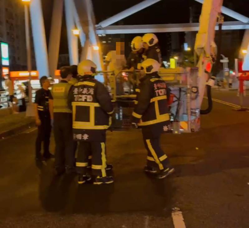 台中市1名男子晚間突然爬上旱溪的金母橋,所報消防人員用雲梯車將他救下。圖/民眾提供 台中市1名男子晚間突然爬上旱溪的金母橋,所報消防人員用雲梯車將他救下。圖/民眾提供