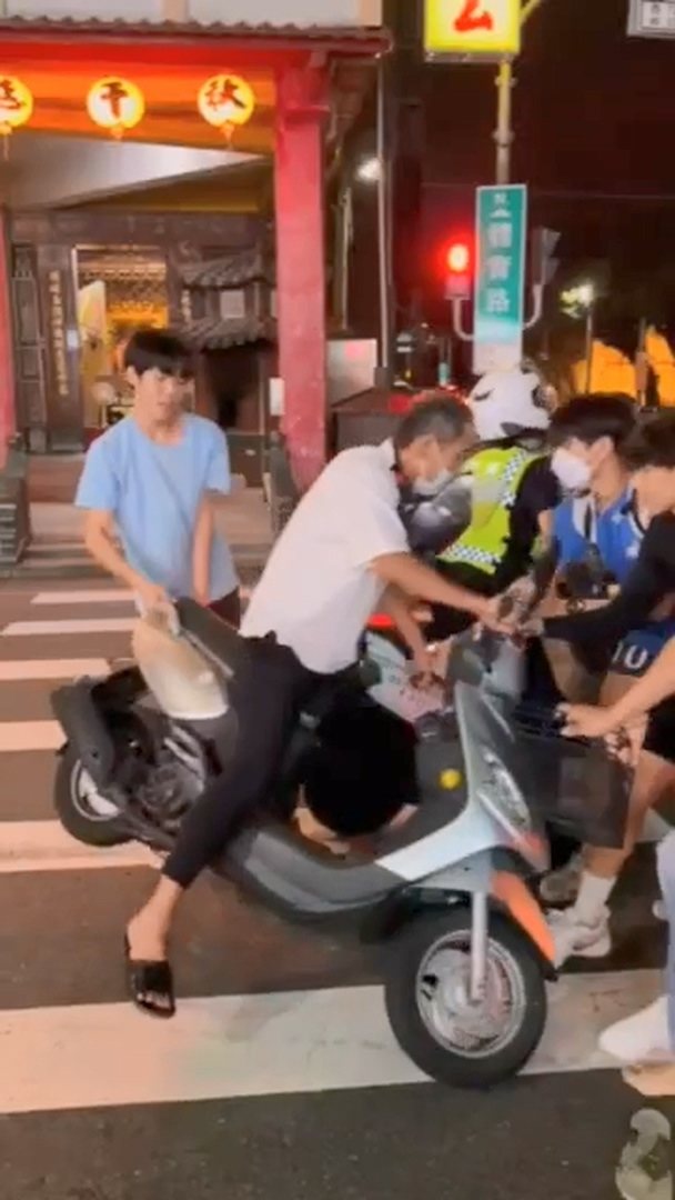 見義勇為的學生和民眾圍住騎士,拉機車、拉人,協助女警將騎士攔下。圖/翻攝畫面 見義勇為的學生和民眾圍住騎士,拉機車、拉人,協助女警將騎士攔下。圖/翻攝畫面
