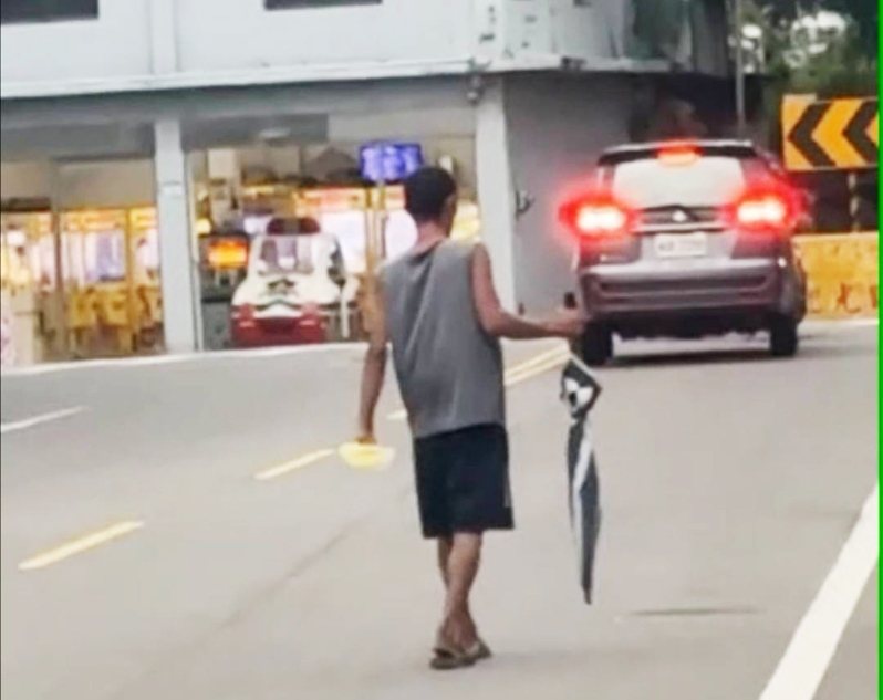 平鎮區潘男精神不穩疑似吸食強力膠，走路中手持雨傘作勢攻擊路人，員警攔下查問。記者曾增勳／翻攝