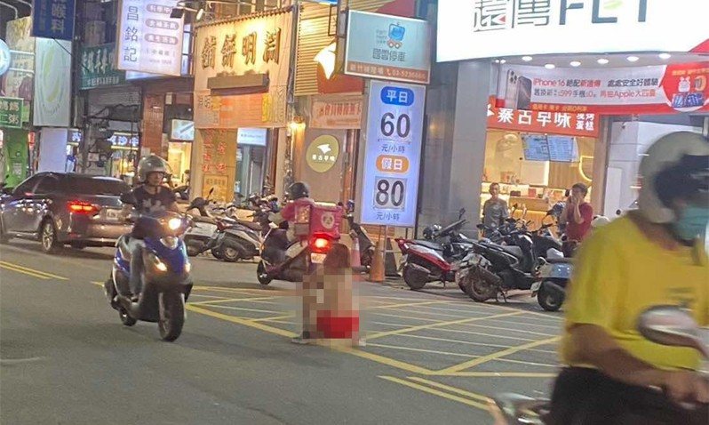 萬聖節大遊行時間還沒到，昨晚竟有一名全身赤裸，僅穿著紅色內褲的裸女在城隍廟商圈嬉遊，甚至直接蹲坐在人來人往的馬路上。圖／取自新竹人新竹事