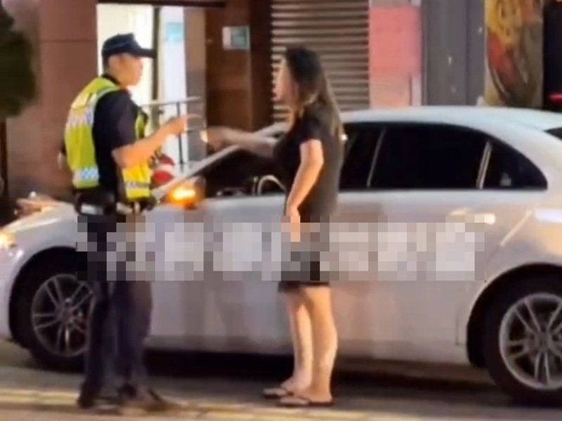 女駕駛駕駛白色轎車行經友愛街口，違規行駛於機慢車專用車道，遭警員予以開單告發，女駕駛違規人簽收舉發單時情緒激動，一度拒收，並和警員爭論後，由同車先生緩頰安撫後，才簽收舉發單倖然離去。圖／翻攝自社會事新聞影音臉書群組