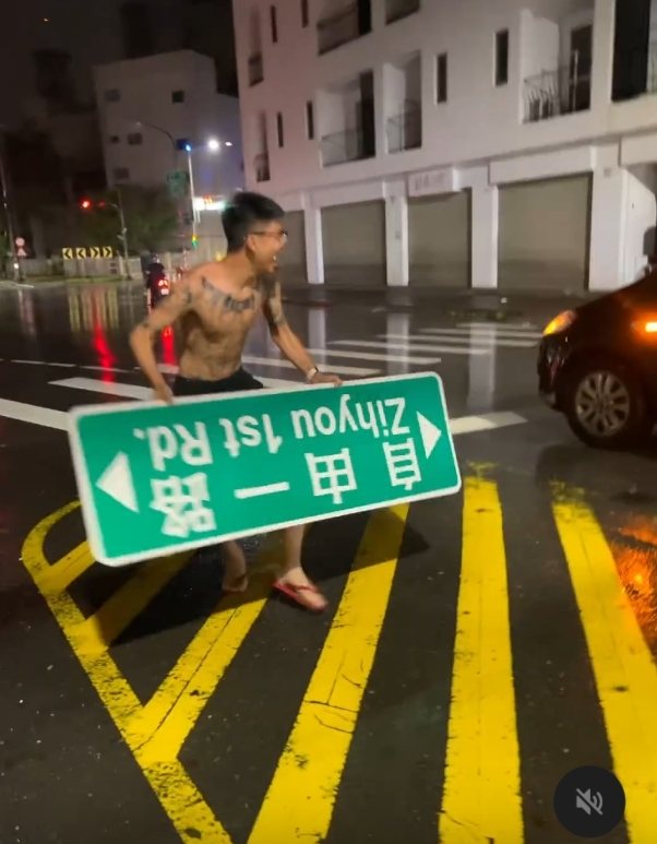 高雄市「自由一路」路牌遭山陀兒強風吹落,一名男子拾起,當街玩了起來。圖/取自社群Threads 高雄市「自由一路」路牌遭山陀兒強風吹落,一名男子拾起,當街玩了起來。圖/取自社群Threads